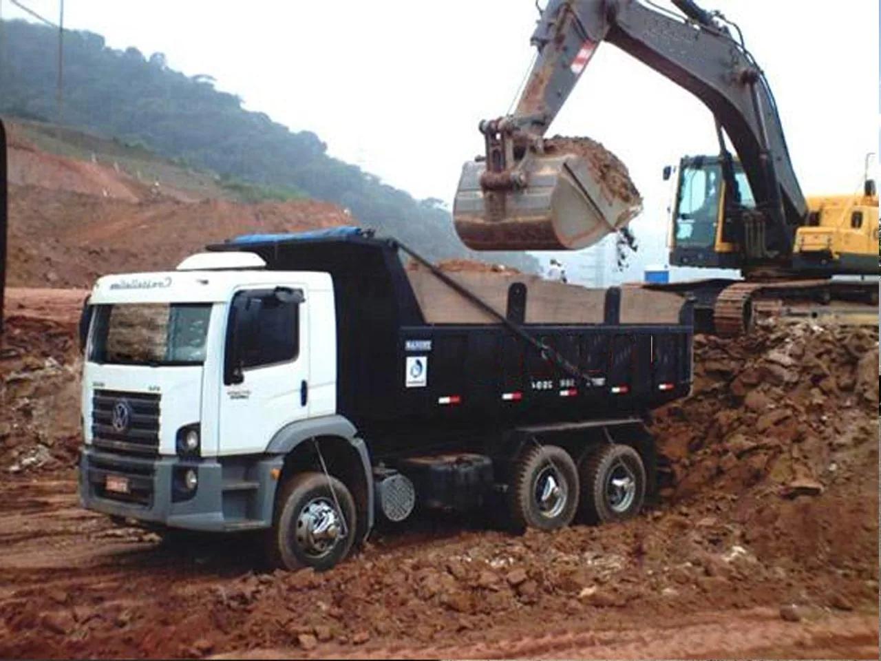 Caminhão basculante carregando terra em obra